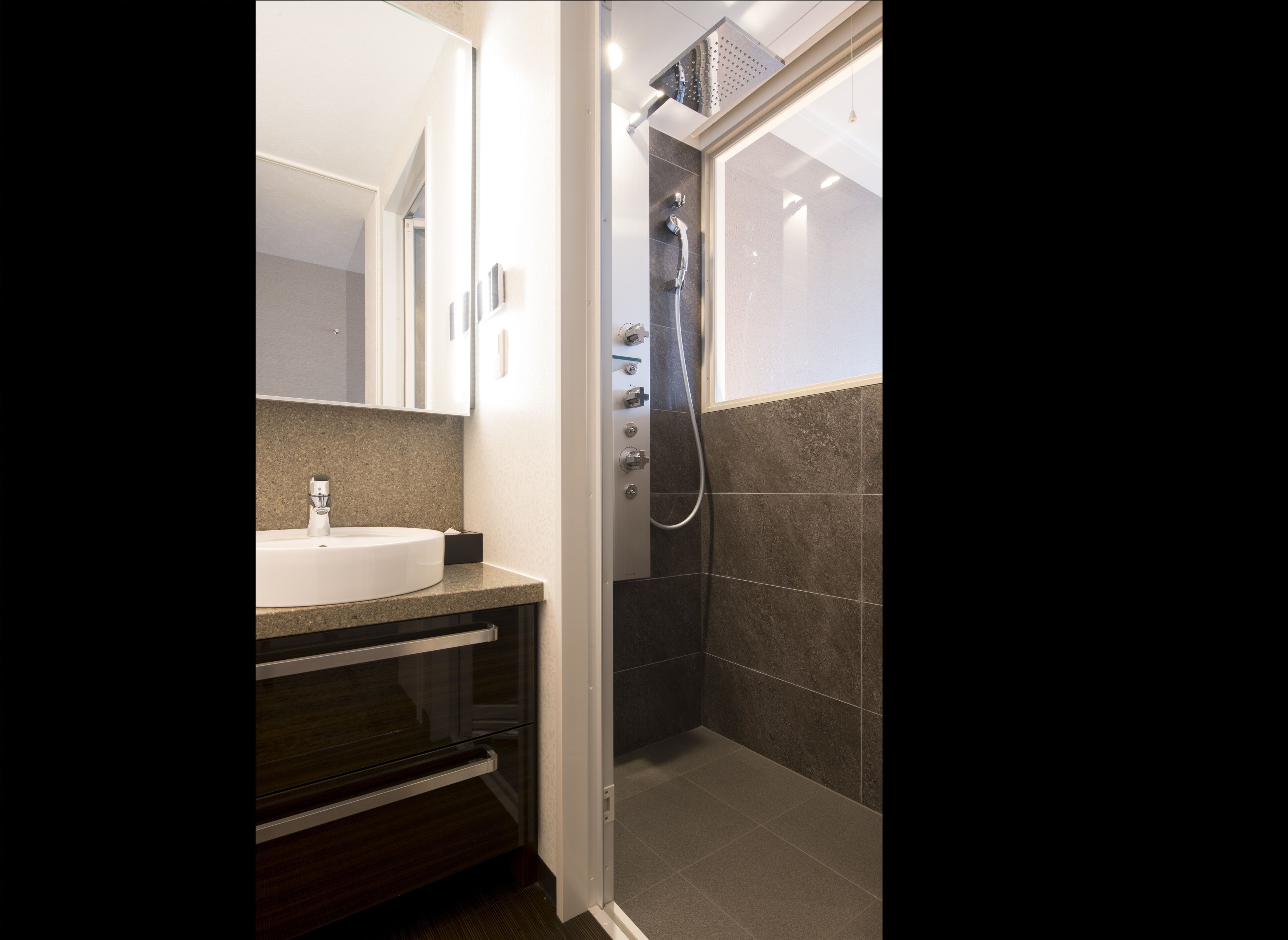 A modern bathroom with a sink, mirror, and shower.