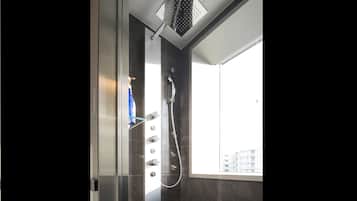 A modern shower with a rain showerhead, a handheld showerhead, and a handheld shower attachment.