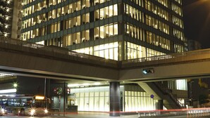 A multi-story building with illuminated windows, a visible entrance, and a pedestrian overpass. - Piazza Hotel Nara (Nara)