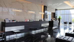 A modern reception area with a marble wall, a reception desk, and a seating area with chairs. - Piazza Hotel Nara (Nara)