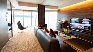 A modern hotel lobby with a large sofa, a television displaying hotel information, and a view of the city through large windows. - Piazza Hotel Nara (Nara)
