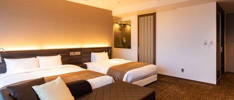 Une chambre d’hôtel avec deux lits, un canapé, un espace douche et un grand miroir.