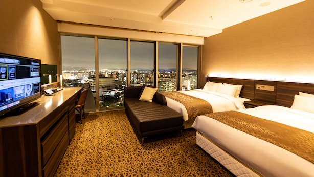 A hotel room with a city view, a desk with a computer, a bed, and a sofa. - Piazza Hotel Nara (Nara)