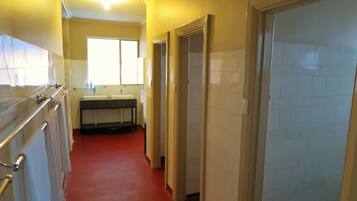 A narrow hallway with a red carpet leading to a bathroom with a sink and mirror.