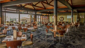 A spacious dining area with numerous tables and chairs, large windows, and a high ceiling with exposed beams. - Pretoria Hotel (Mannum)