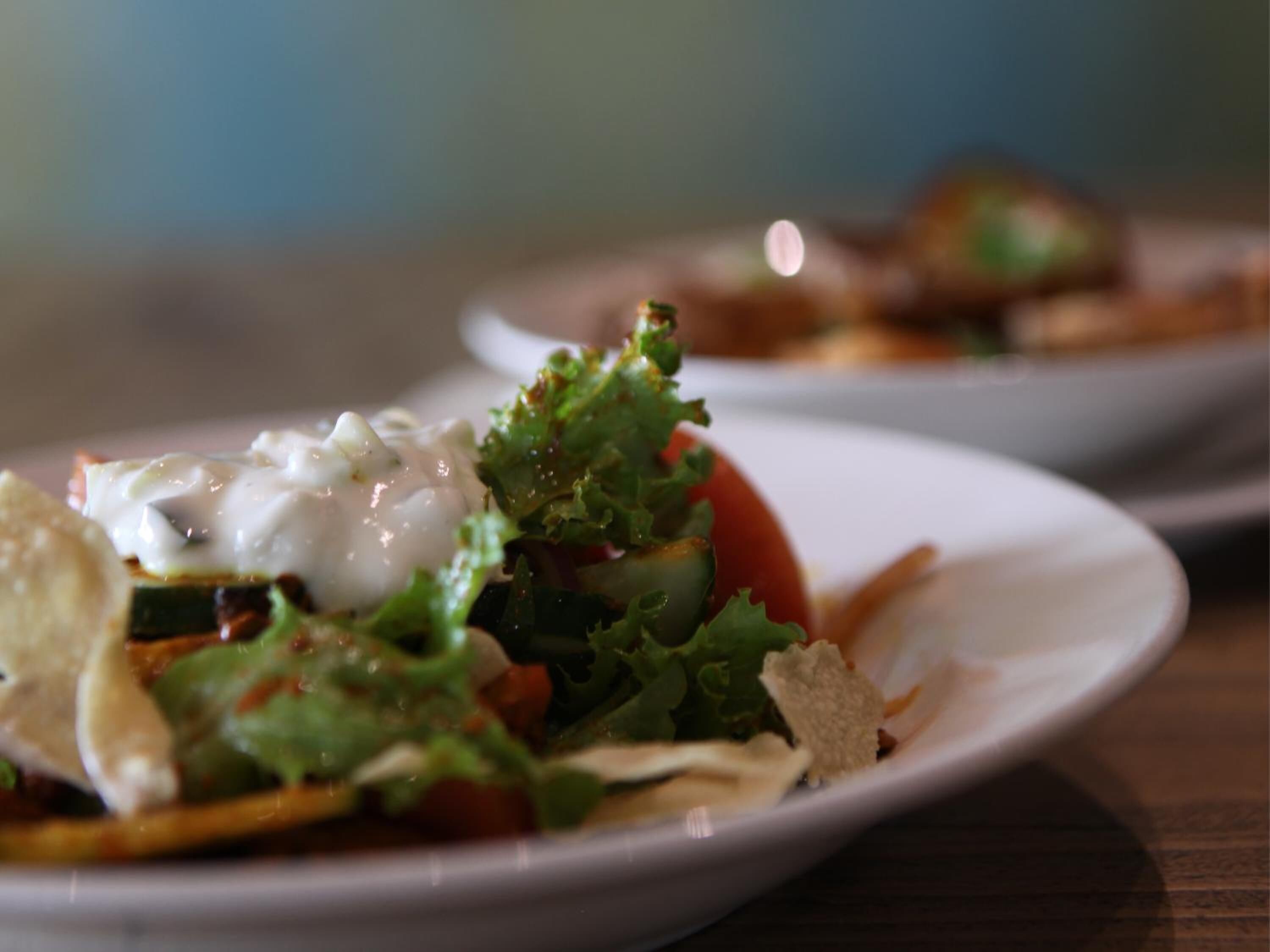 A plate of food with a salad, a dollop of sauce, and some croutons.