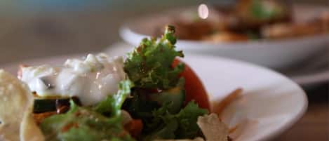 Un plato de comida con ensalada, una cucharada de salsa y algunos crotones.