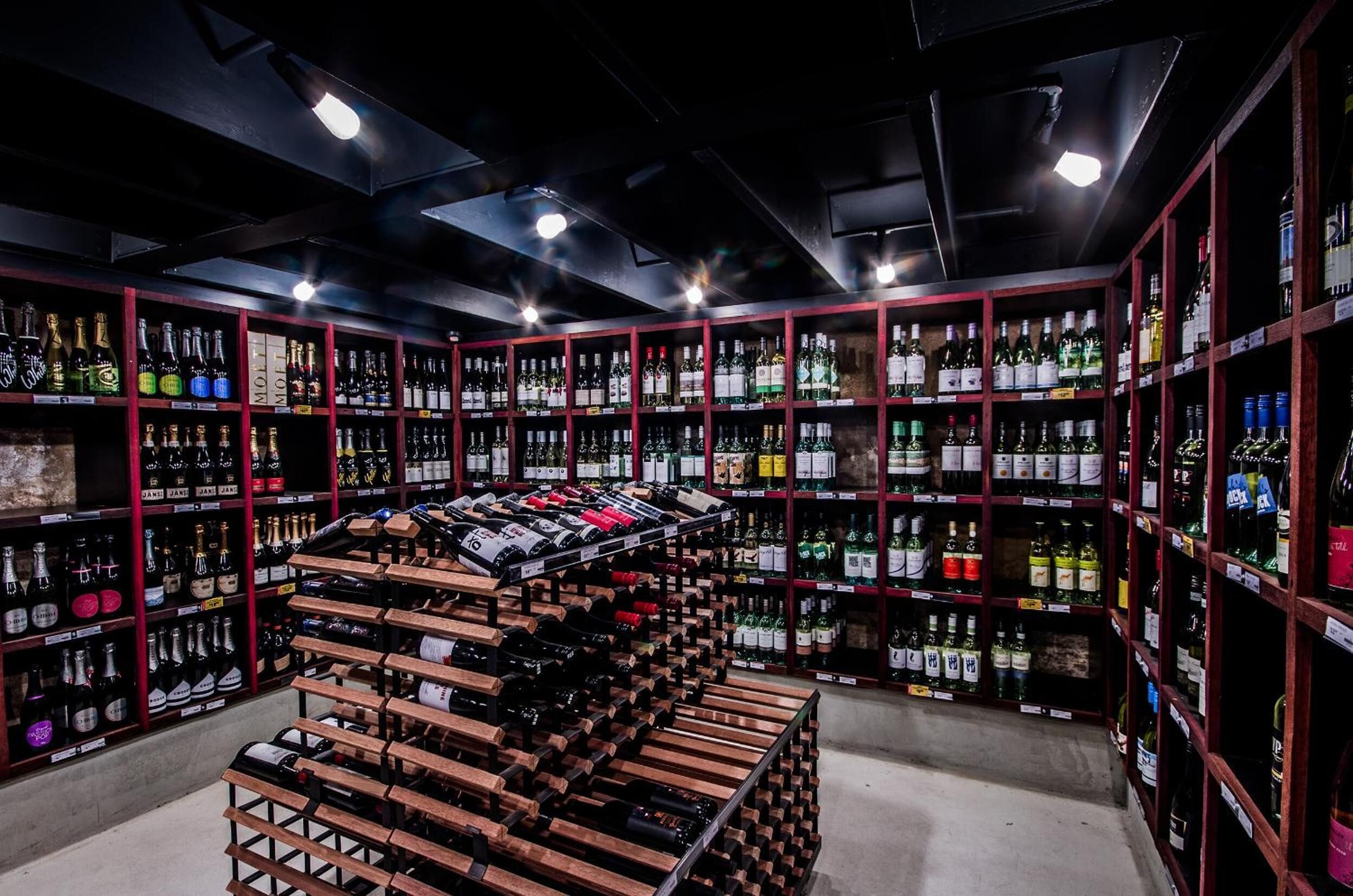 A wine cellar with wooden racks and shelves filled with various bottles.