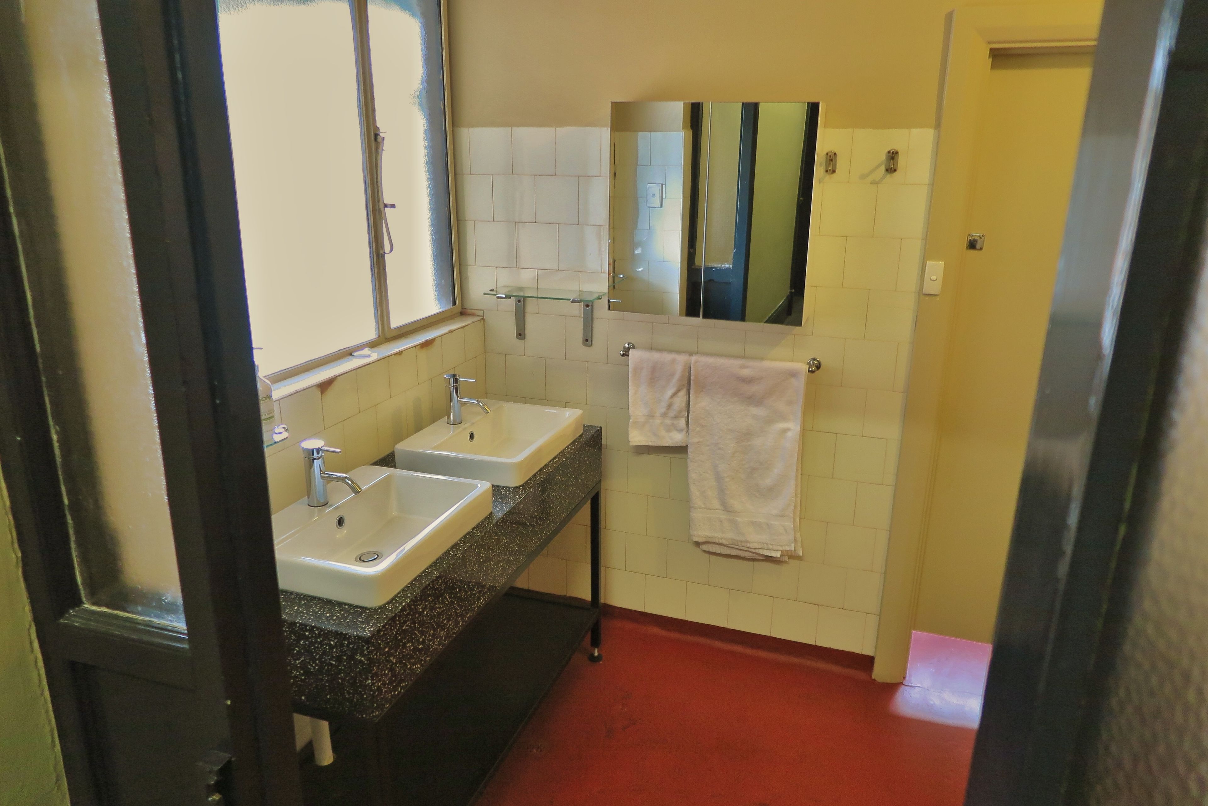 Ein Badezimmer mit zwei Waschbecken, einem Spiegel und einem roten Boden.