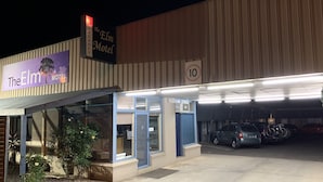 The Elm Motel with a reception area, parking lot, and a sign indicating a speed limit of 10. - Elm Motel (Golden Square)