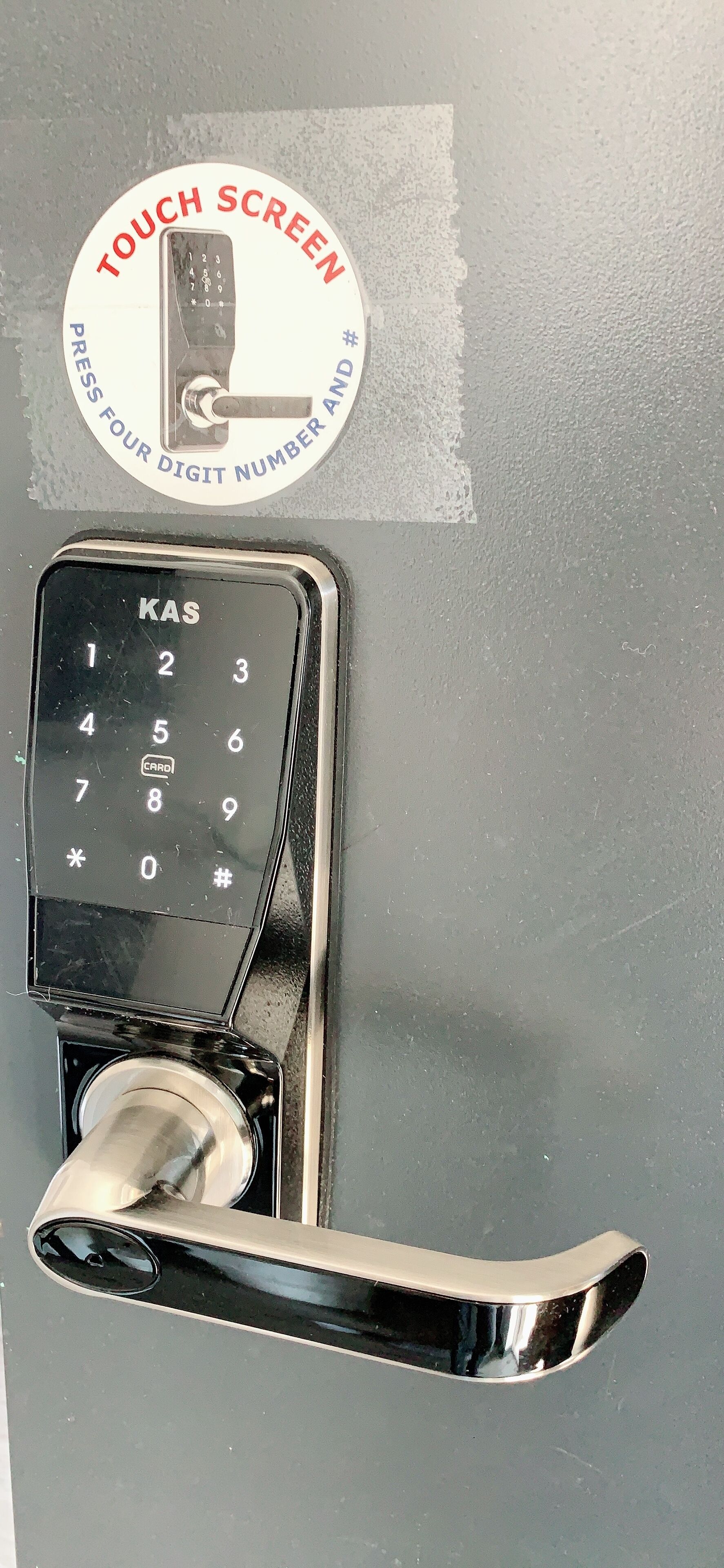 Un teclado táctil con un lector de tarjetas, un picaporte y una etiqueta circular con instrucciones.