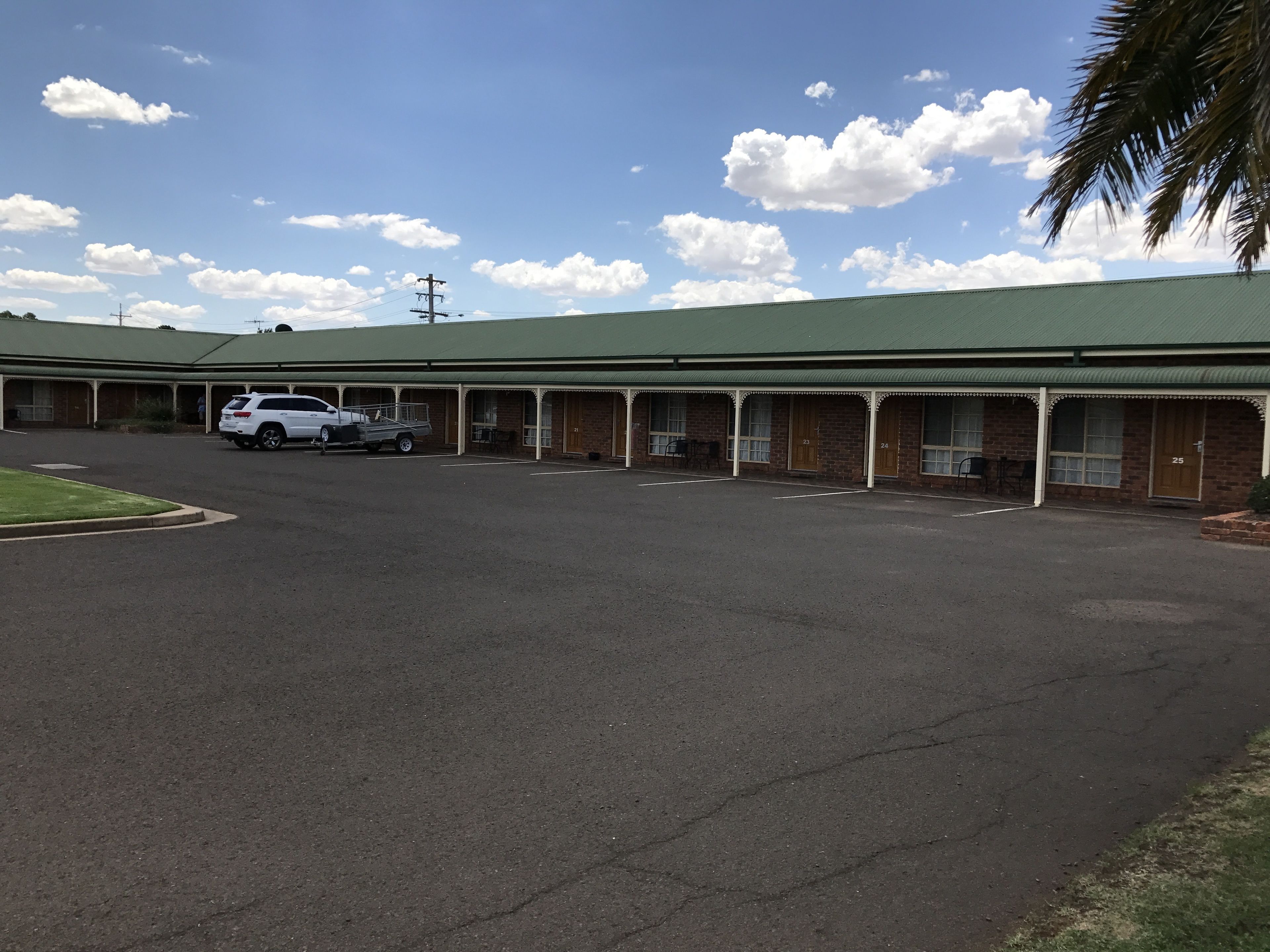 Un motel con techo verde y habitaciones numeradas.