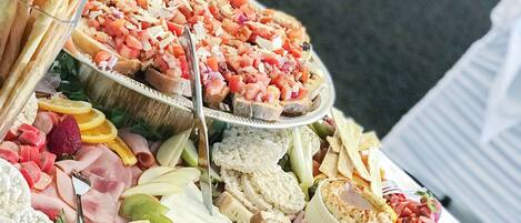 A table with various food items including fruits, cheeses, and meats, arranged for a buffet.