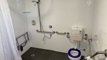 A bathroom with a shower, grab bars, a toilet with a blue seat, and a glass shower enclosure.