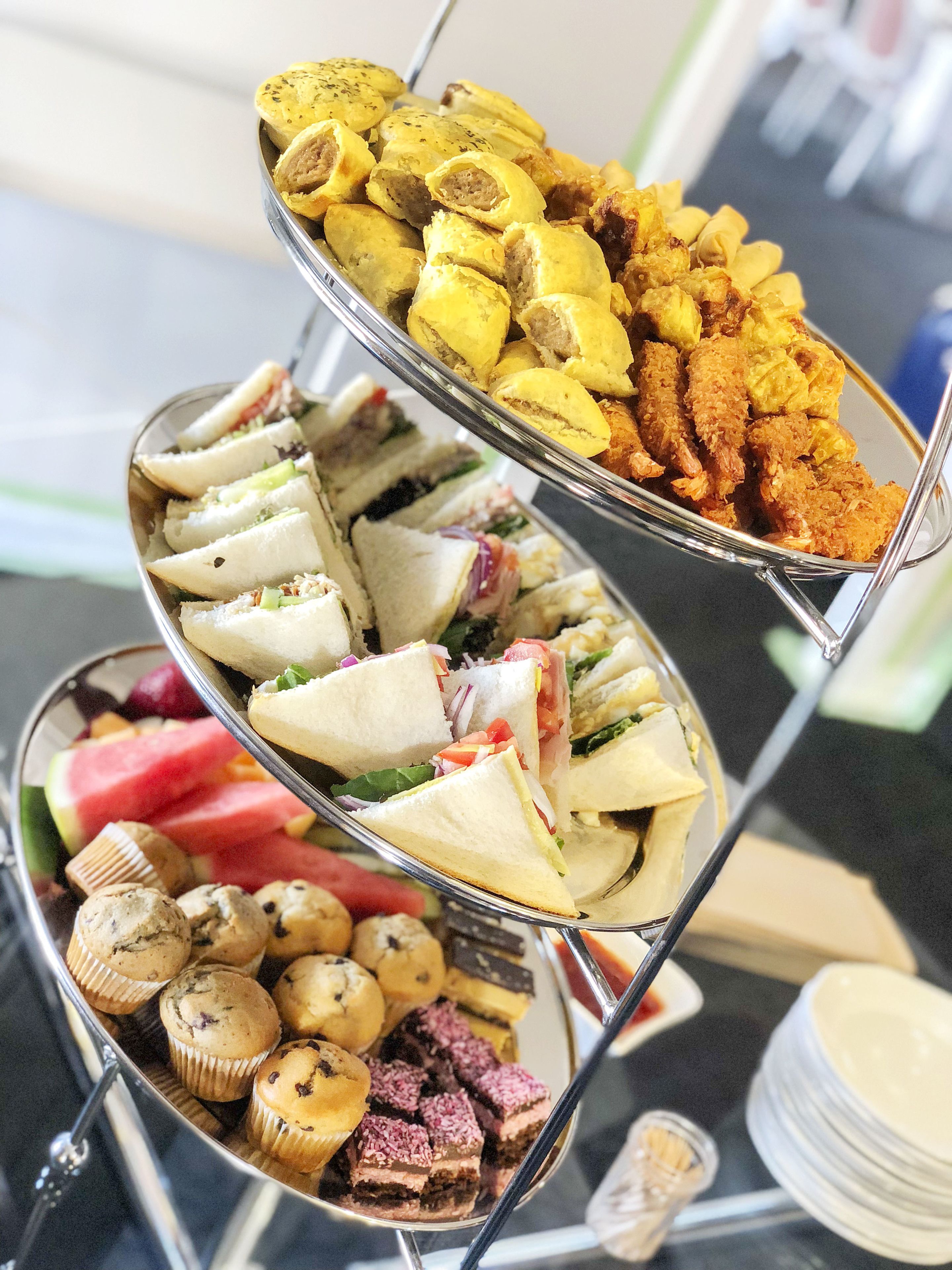 Un bufé con diversos alimentos, entre ellos sándwiches, muffins y opciones fritas.