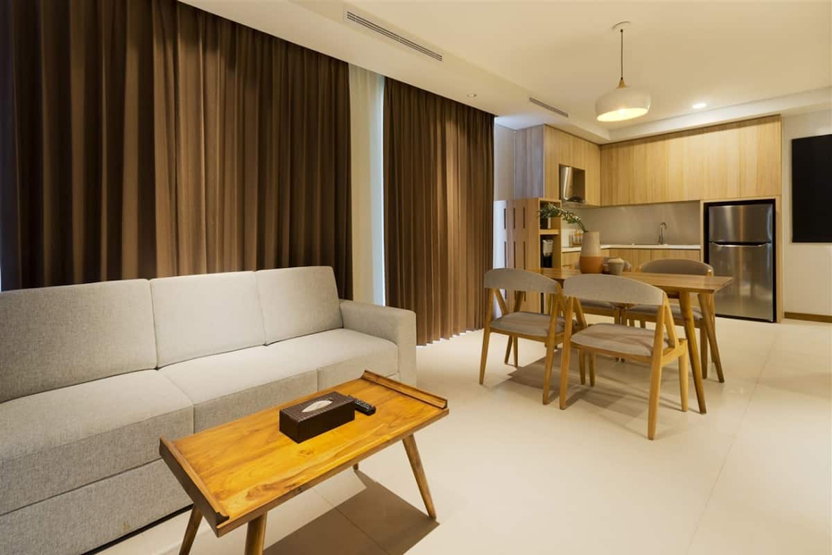 A modern living room with a sofa, wooden coffee table, and a dining area with chairs and a table.