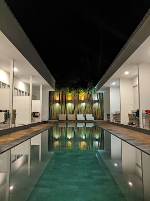 A modern indoor pool with clear water, surrounded by white walls and wooden flooring. - Villa Phyphy 2 (Gili Trawangan)