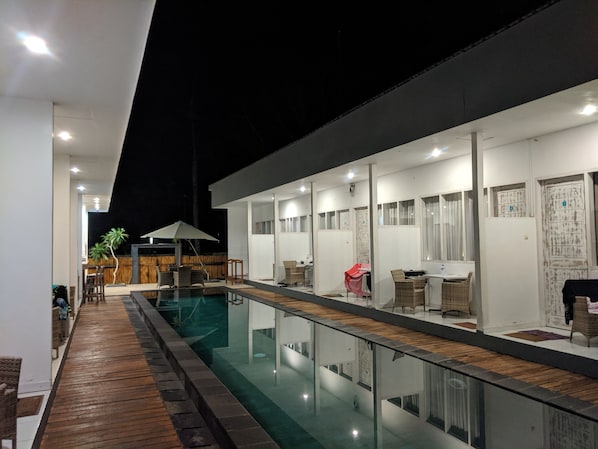 A modern hotel with a pool, wooden deck, and outdoor seating area. - Villa Phyphy 2 (Gili Trawangan)