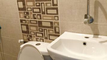 Un baño con inodoro, lavamanos y azulejos con diseño.
