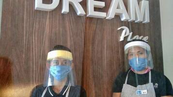 Dues persones portant delantals i protectors facials de peu davant d'un rètol de fusta que diu "My Dream Place".