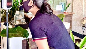 Una persona en una habitación con una decoración moderna, que incluye un expositor de vidrio, una planta verde grande y un adorno sobre una encimera.