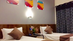 Habitación de hotel con dos camas, una mesita de noche, una lámpara y una luz empotrada en la pared.