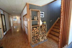 A hallway with wooden flooring, a wooden display case with items, and a staircase. - Kaiya Nozawa (Nozawaonsen)