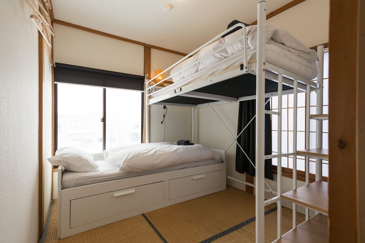 A bunk bed room with a window, a desk, and a chair.