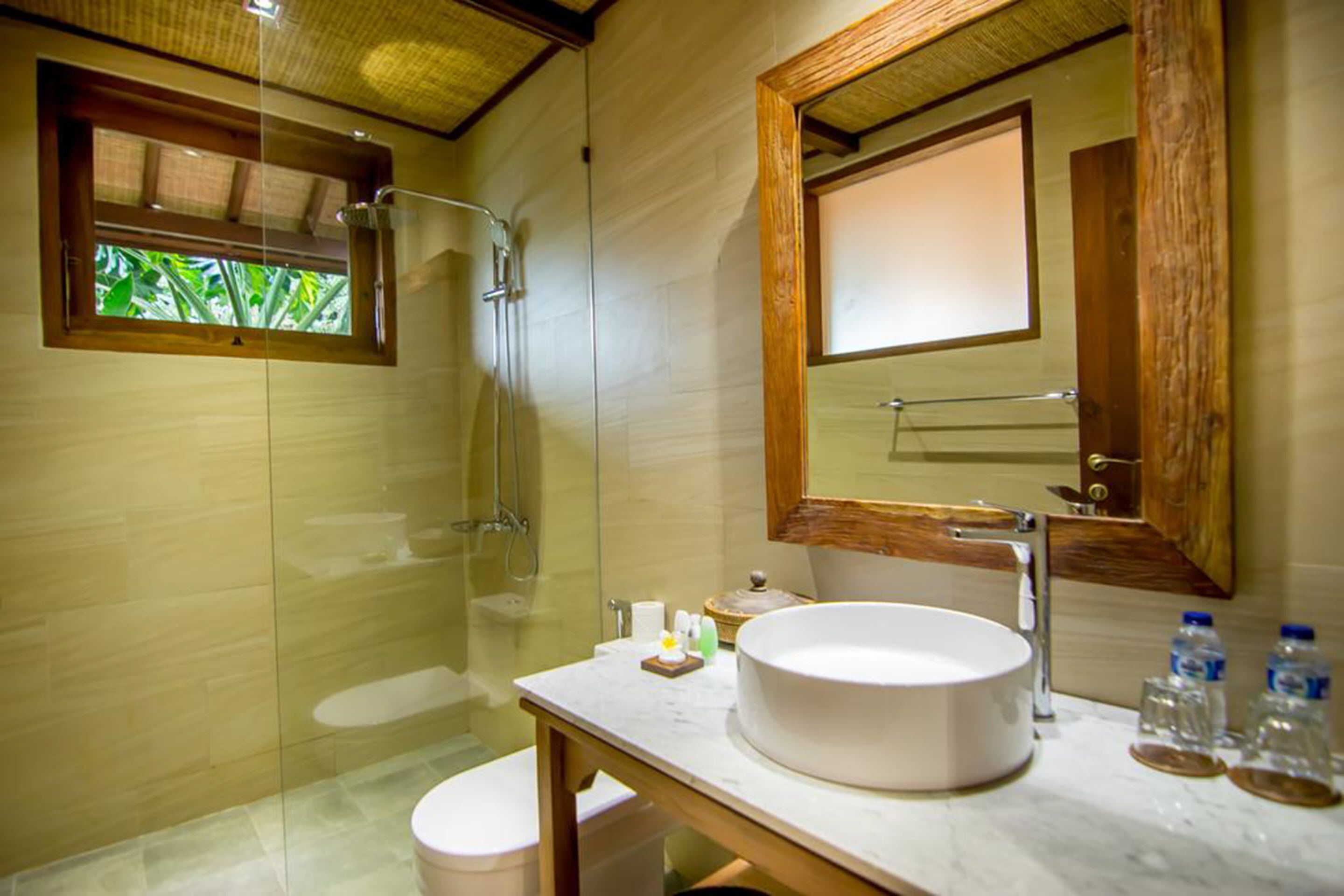 Ein modernes Badezimmer mit einer begehbaren Glasdusche, einem runden Waschbecken und einem großen Spiegel.