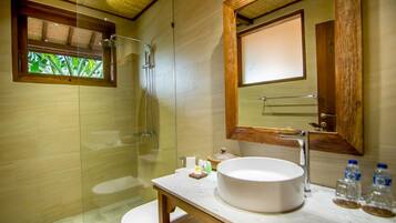 Ein modernes Badezimmer mit einer begehbaren Glasdusche, einem runden Waschbecken und einem großen Spiegel.