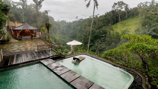 Una piscina con maderas, una silla de descanso y una sombrilla.