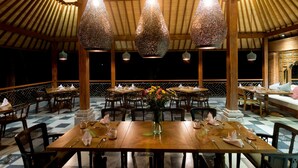 Un restaurante con mesas y sillas de madera, lámparas colgantes y piso a cuadros.