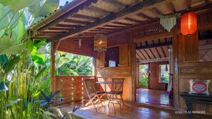 A wooden interior with a wooden table and chairs, a hanging light fixture, and a red lantern. - Hati Padi Cottages (Payangan)