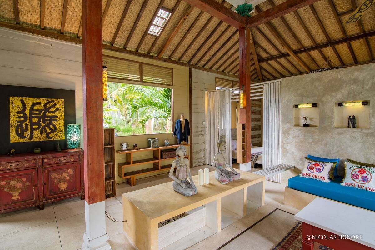 A traditional interior with a wooden ceiling, a central bench, and a sofa with decorative pillows.
