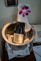 A bottle of wine labeled "TORRESSELLA PROSECCO DOC" in a metal bowl with a cloth napkin and a purple orchid.