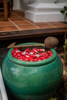 A green ceramic pot filled with red and white pebbles and a wooden spoon.
