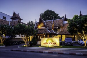 A resort with traditional architecture, a signboard, and parked cars.