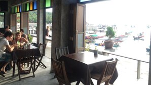A restaurant with a view of boats on water, wooden tables, and chairs. - Bro&Sis Place (Koh Tao)