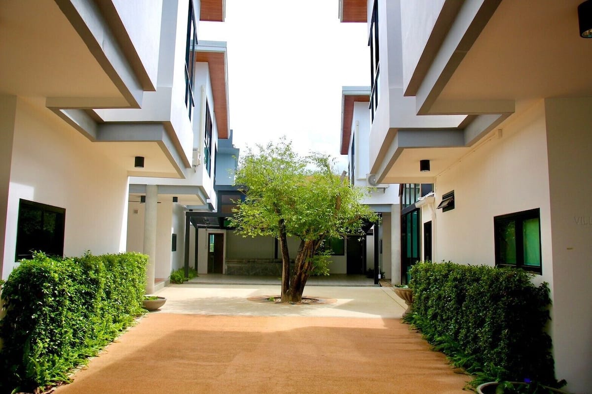 A modern building with a central courtyard, featuring a tree and neatly trimmed hedges.