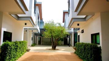 Un edificio moderno con un patio central, que presenta un árbol y setos bien cuidados.