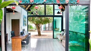 Un espacio de oficina moderno con un escritorio, sillas y un amplio ventanal con vistas a un jardín.