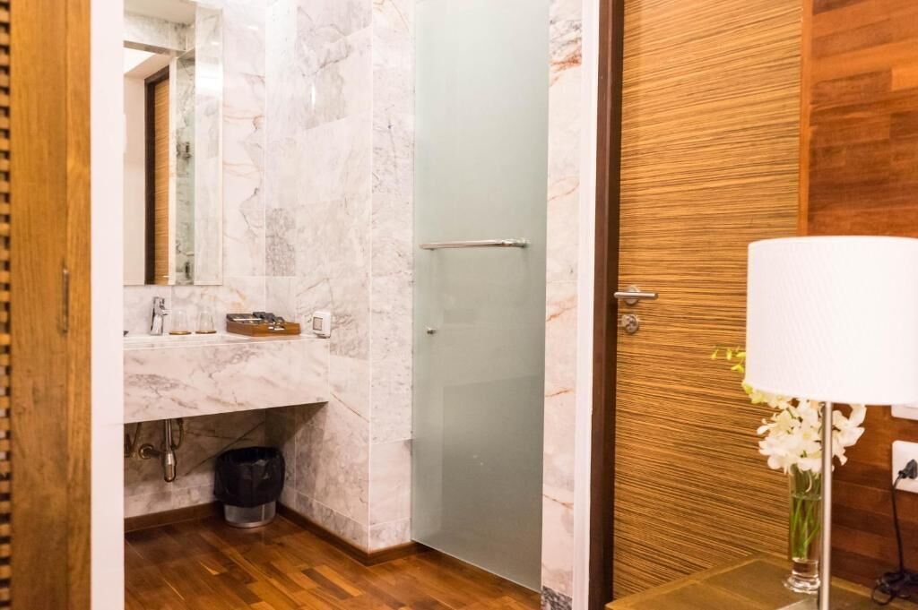 A bathroom with a marble sink, a glass shower enclosure, and a wooden door.