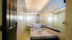 A bedroom with a bed, a large mirror, and a wardrobe. - JJ Midcity Inn (Tabaco City)