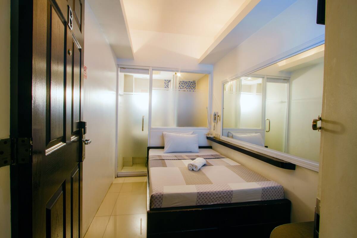 A bedroom with a bed, a large mirror, and a wardrobe.