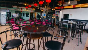 A restaurant interior with round tables and chairs, red hanging lanterns, and a counter area with a menu display. - JJ Midcity Inn (Tabaco City)