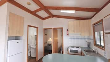 A compact kitchen with wooden cabinets, a built-in microwave, and a sink.