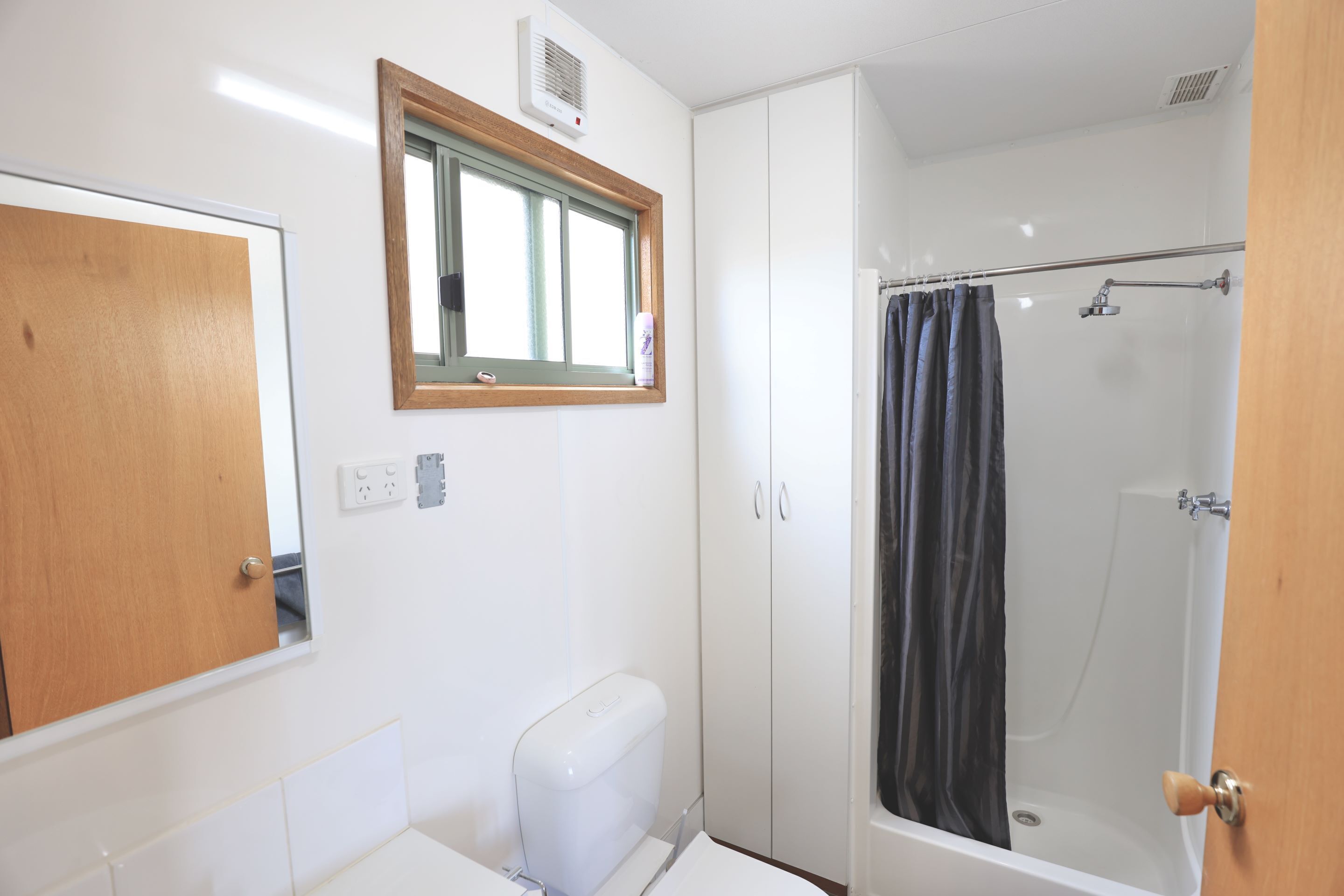A bathroom with a toilet, a shower, and a window.