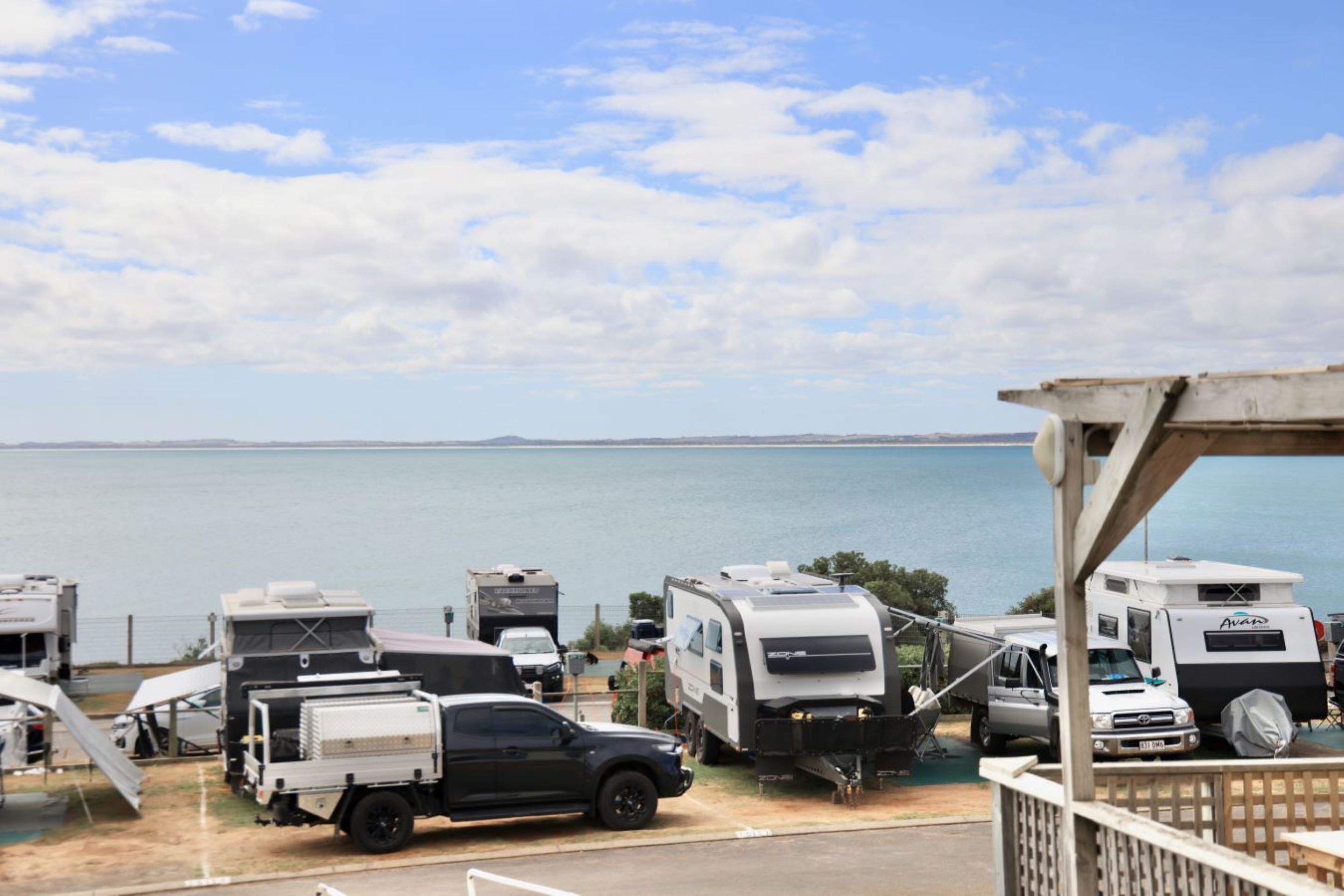 A caravan park with multiple caravans and a black truck parked near the water.