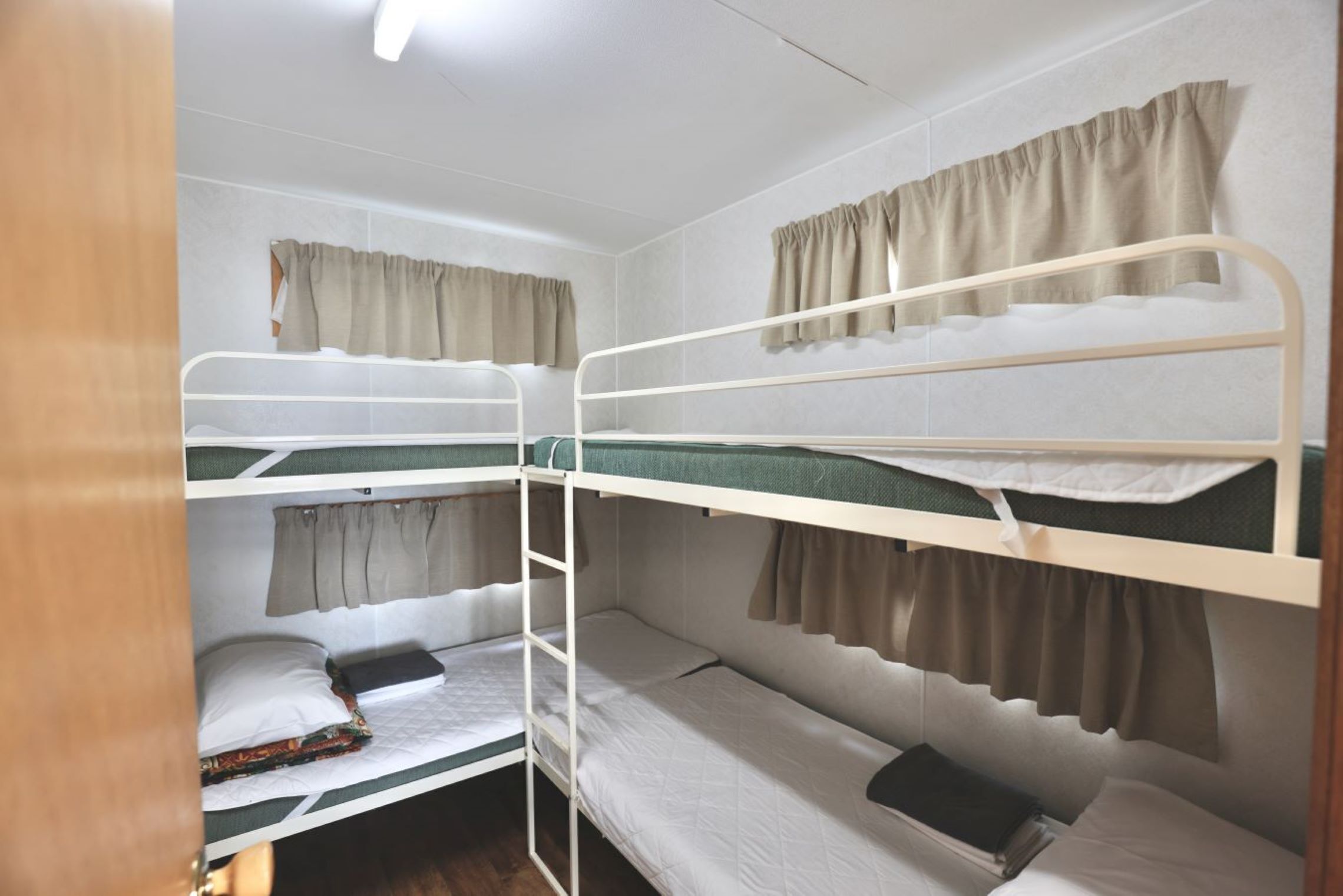 A bunk bed room with three levels, each with a curtain.