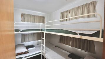 A bunk bed room with three levels, each with a curtain.
